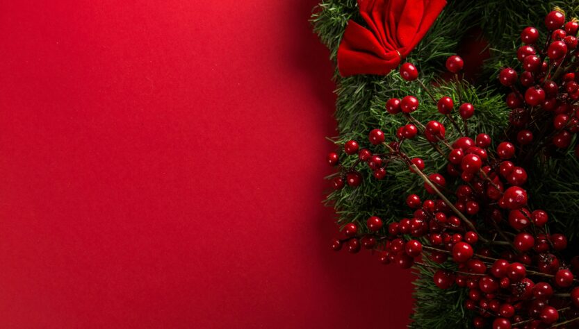 Red and green Christmas wreath against a red background